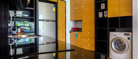 A modern kitchen with a stainless steel refrigerator, a sink, and a washing machine.