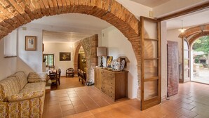 Ein gemütliches Wohnzimmer mit einer Ziegelbogenarchitektur, einer Couch, einem Holzschrank und einem Essbereich.