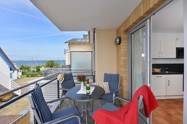 A balcony with a table, chairs, and a bottle of champagne.