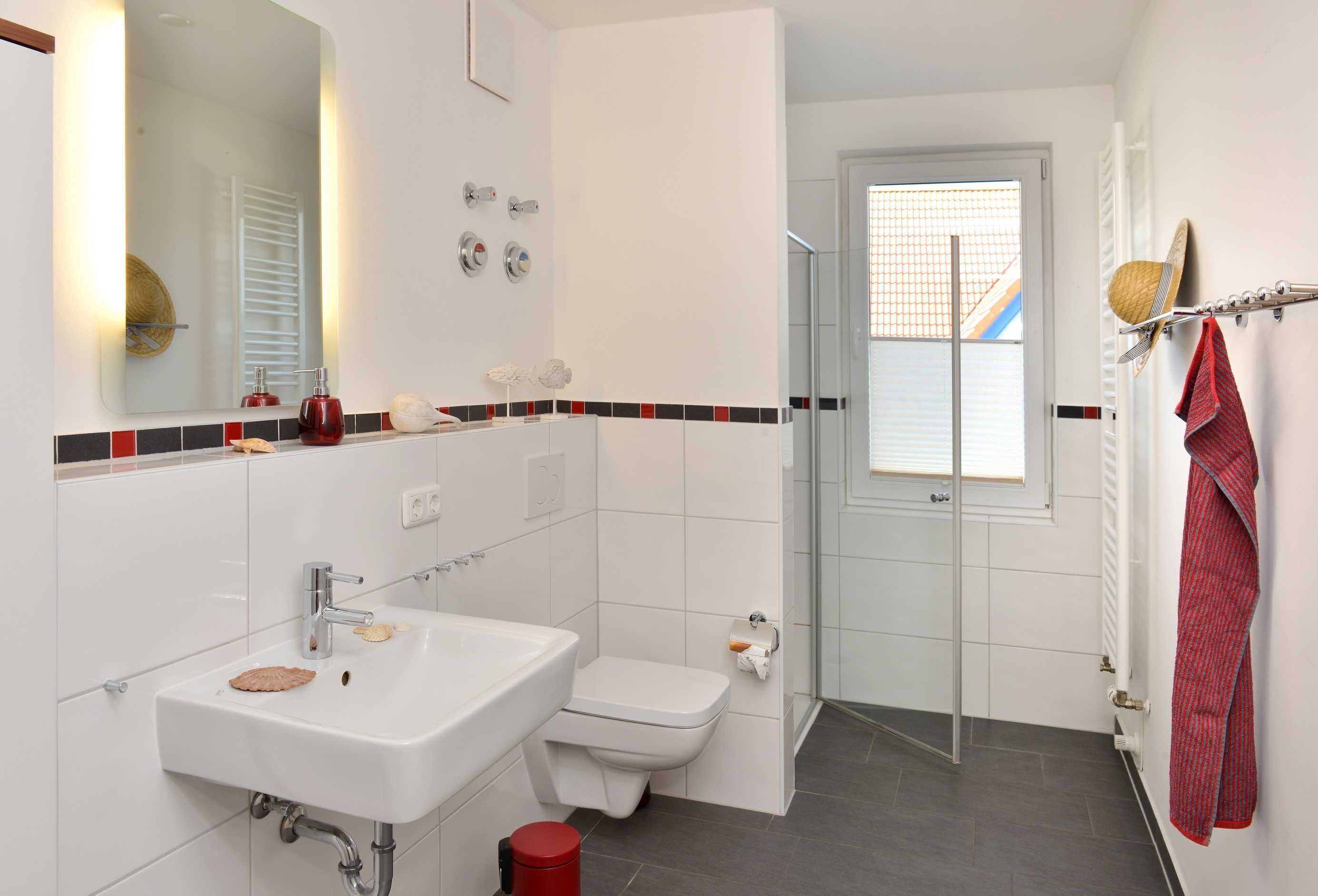 A modern bathroom with a white sink, toilet, and shower area.