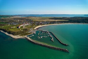 Ein Luftbild einer Küstenstadt mit einem Yachthafen, Häusern und einem Strand.