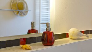 A bathroom with a mirror, a red soap dispenser, and a white soap bar on the counter. - Bernstein Suite—right on the beach! - Bernstein Suite (Glowe)