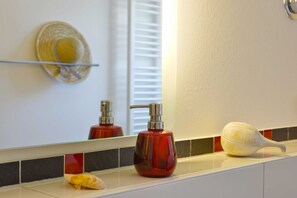 Ein Badezimmer mit Spiegel, rotem Seifenspender und einer weißen Seife auf der Ablagefläche.