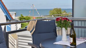 A balcony with a view of the sea, a table with a bottle of wine, and a vase of flowers. - Bernstein Suite—right on the beach! - Bernstein Suite (Glowe)