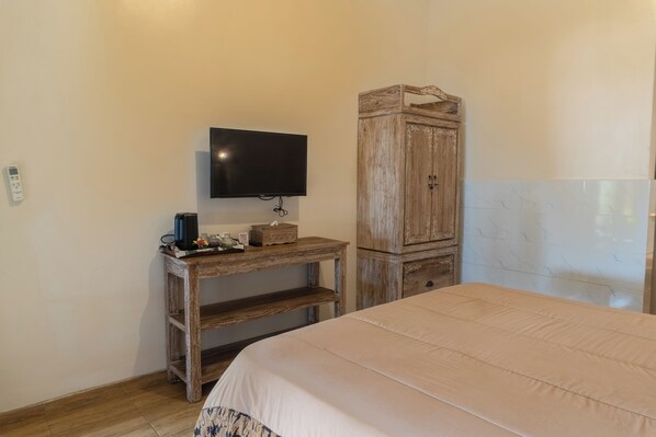 A bedroom with a bed, a wooden desk with a television, and a wardrobe.
