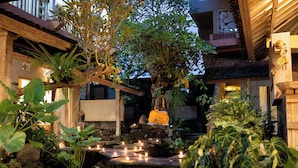 Un jardín tranquilo con fuente de agua, escalones de piedra y plantas en macetas.