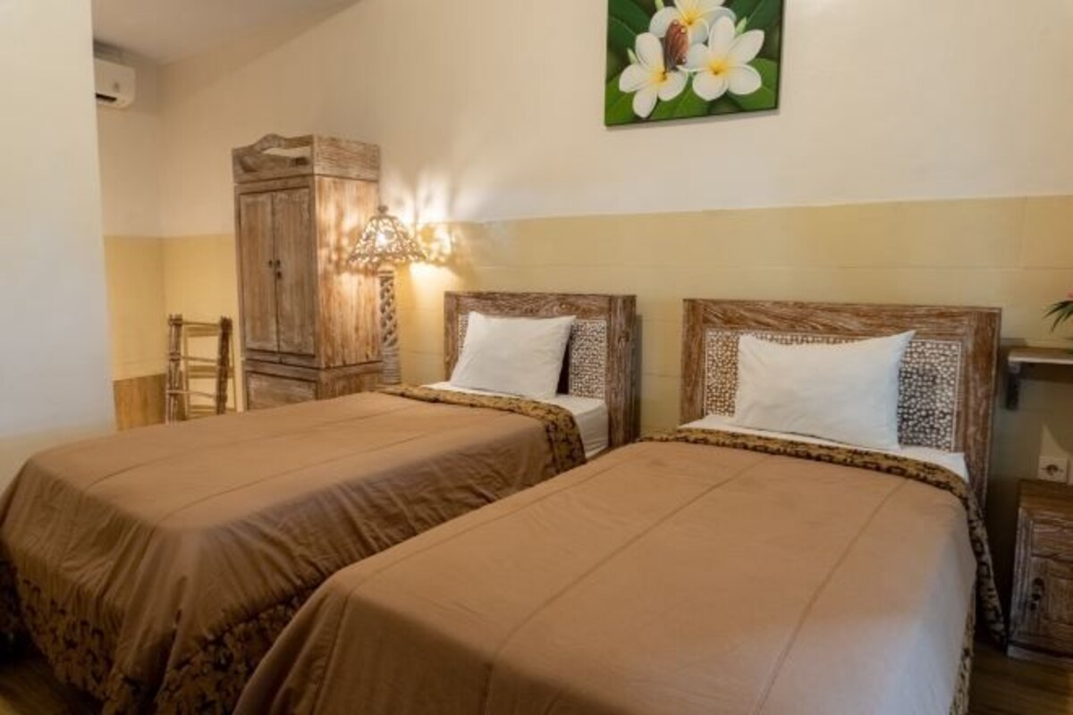 Une chambre avec deux lits, des têtes de lit en bois et une table de chevet avec une lampe.