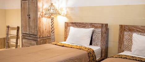 Une chambre d’hôtel avec deux lits, une armoire en bois et une lampe décorative.
