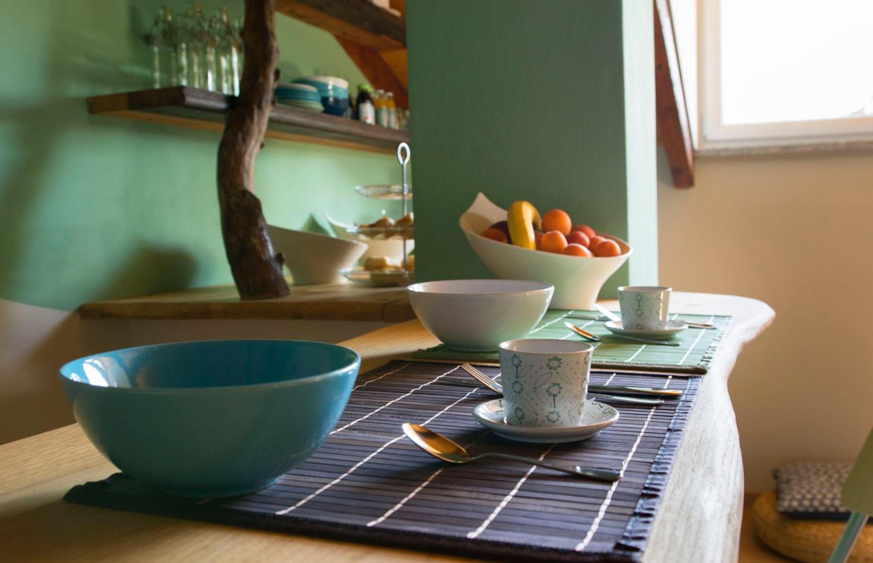 A dining table with a blue bowl, a white bowl, and a teacup on a placemat.
