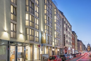 Un hotel de varios pisos con fachada moderna, amplias ventanas y un letrero visible que dice 'HAPIMAG'.