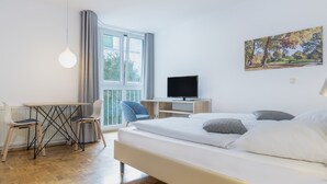 A modern bedroom with a bed, a desk, and a television. - Hapimag Resort München (Munich)