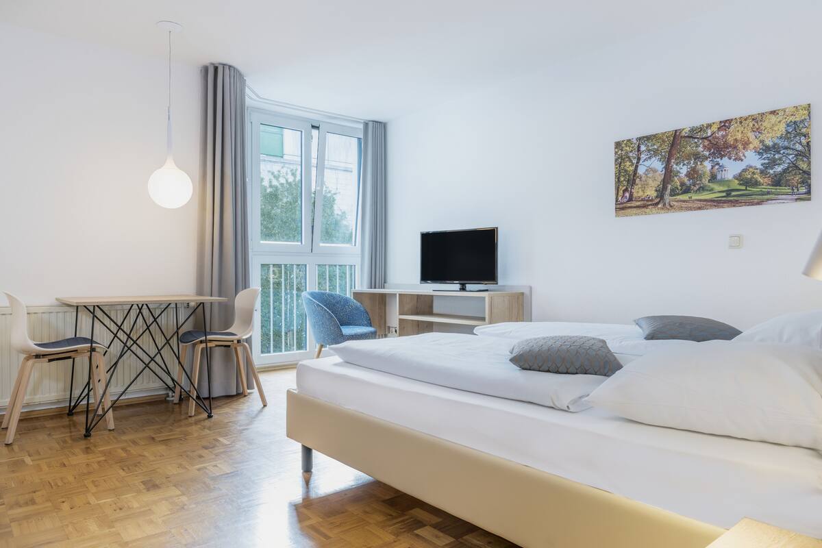 Una camera da letto moderna con un letto, una scrivania e una televisione.