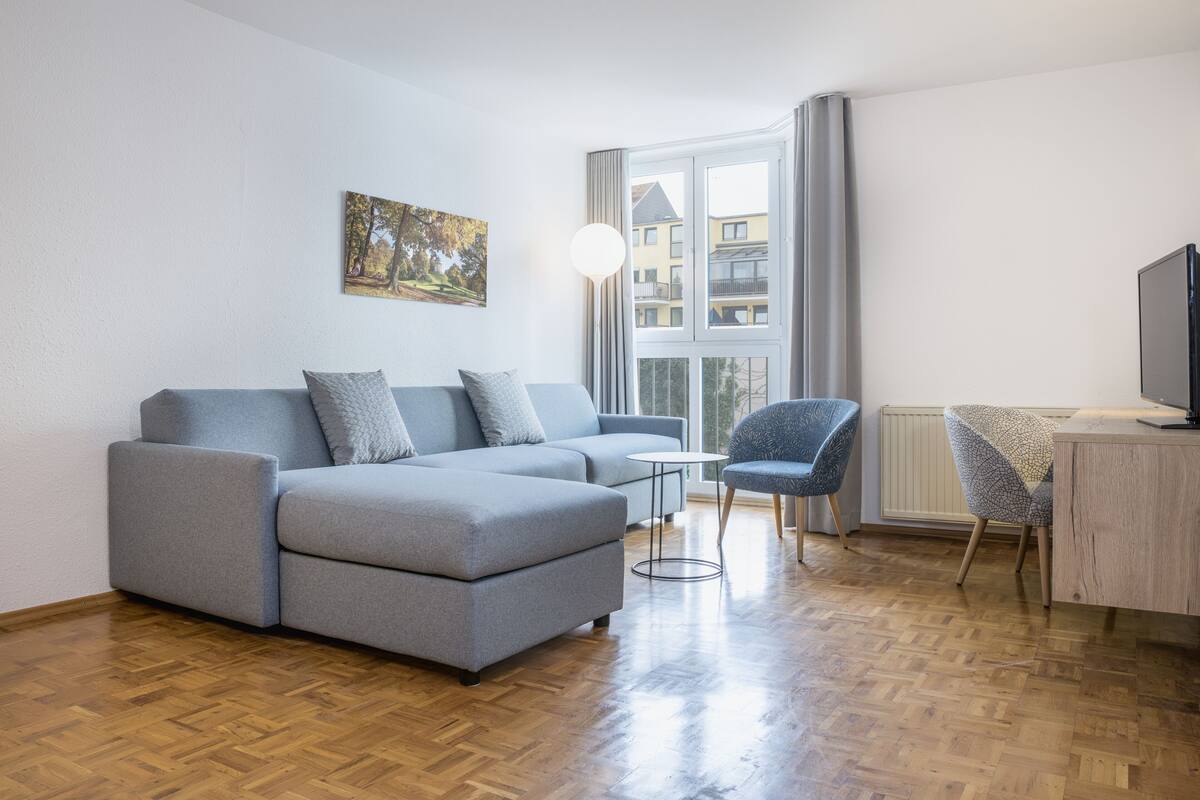 Un soggiorno moderno con un divano grigio, un tavolino rotondo e una poltrona blu.