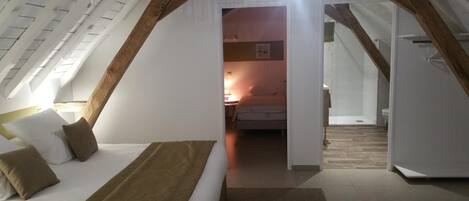 Un dormitorio con techo inclinado, una cama con almohadas, una mesita de noche y una lámpara colgante.
