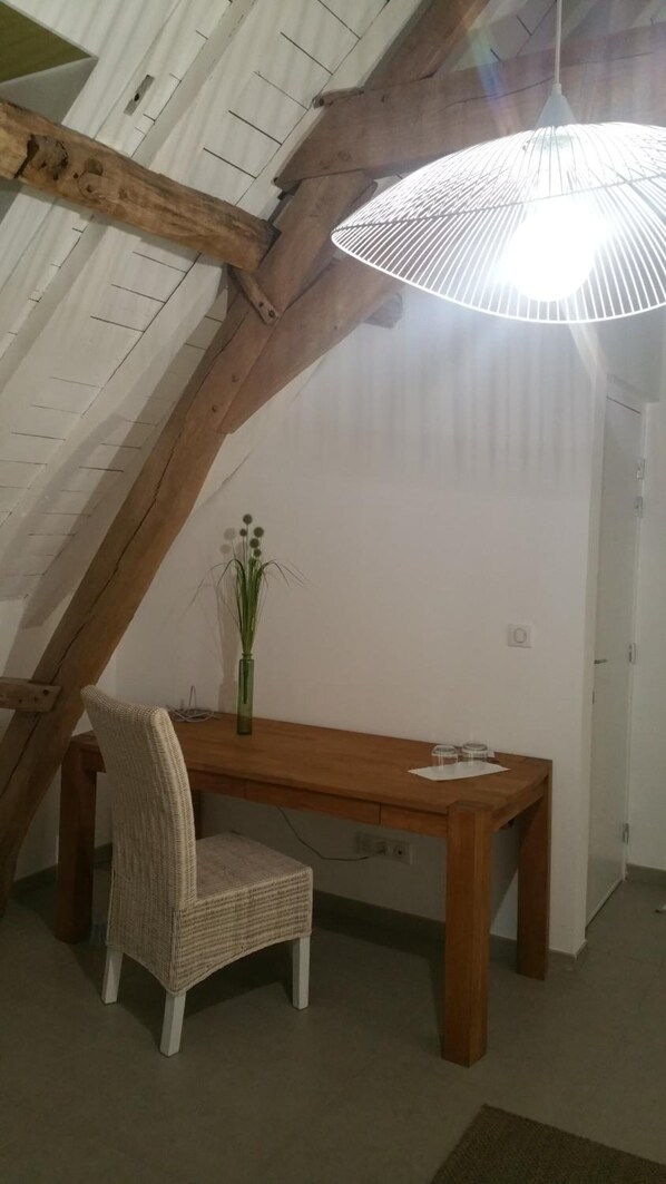 A dining area with a wooden table and chair, a vase with flowers, and a hanging light fixture. - La Cense Pierrot des Princes (Saint-Amand-les-Eaux)