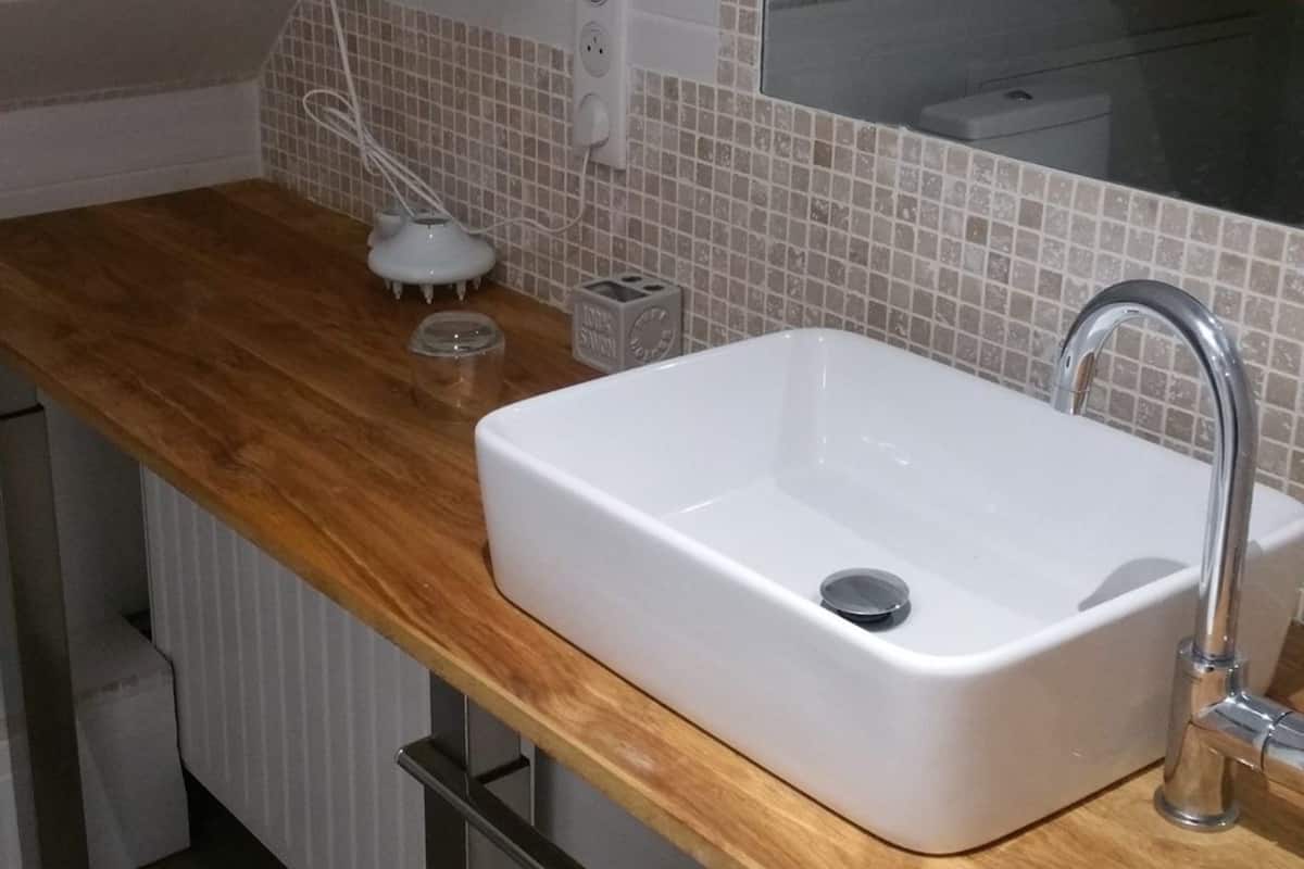A modern bathroom with a wooden countertop, a white sink, and a mirror above it.