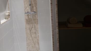 Een moderne badkamer met een douche, betegelde wanden en een houten balk in het plafond.