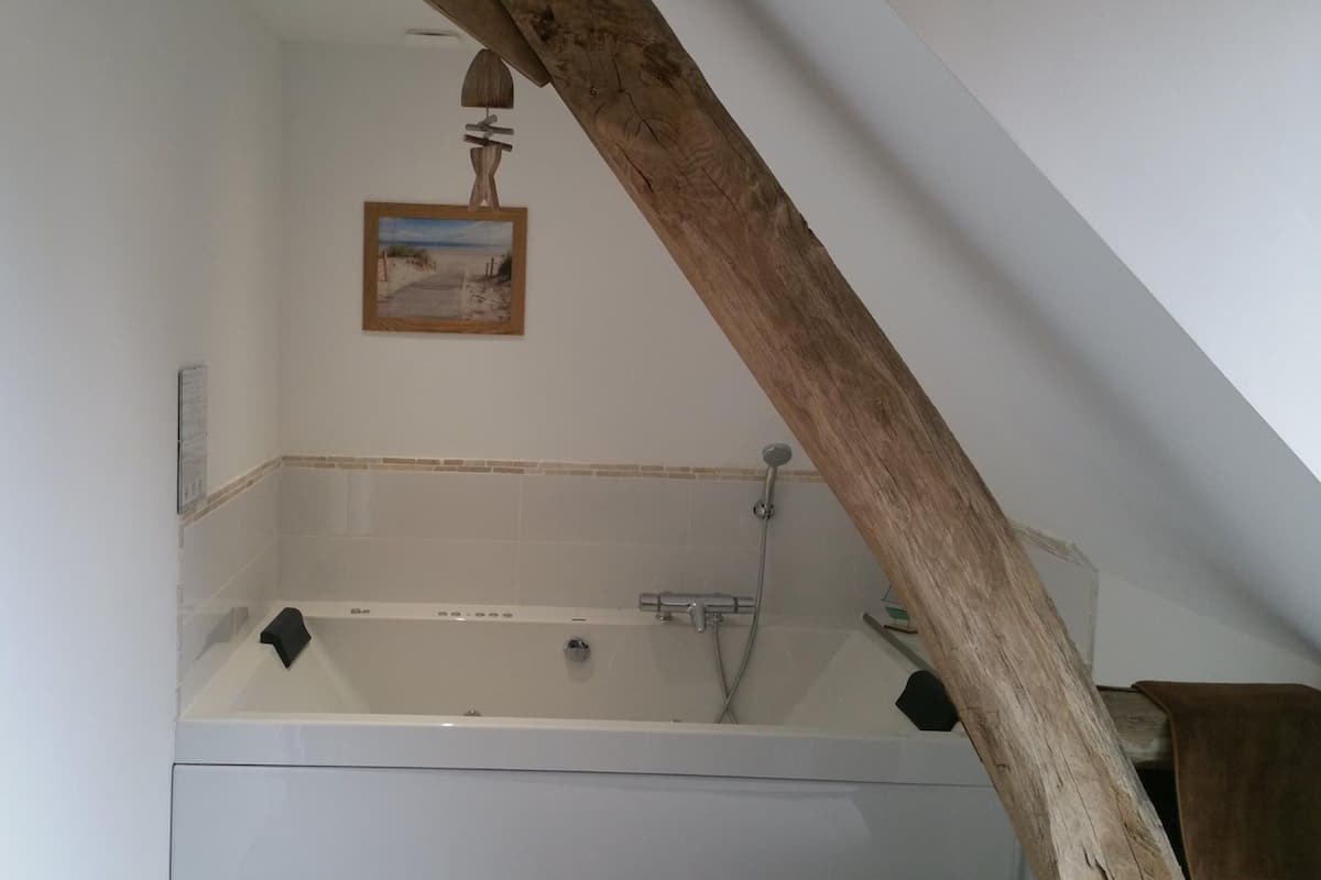 A bathroom with a bathtub, a wooden beam, and a picture on the wall.