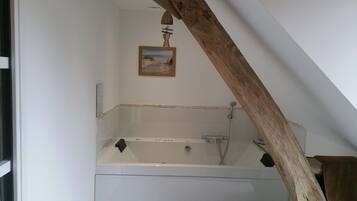 Un baño con bañera, una viga de madera y un cuadro en la pared.