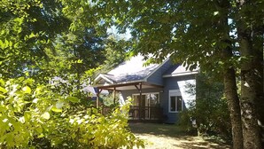 Une maison dotée d’un porche abrité, entourée d’une végétation luxuriante et d’arbres.