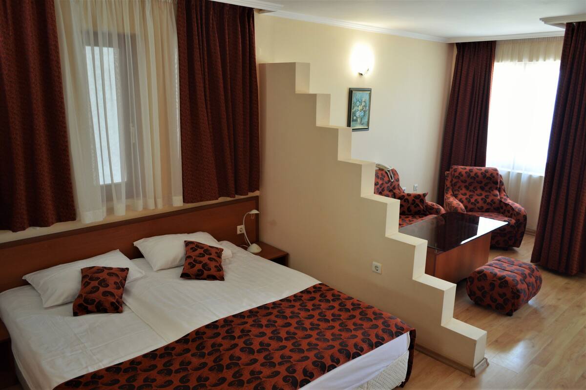 A hotel room with a bed, a chair, and a staircase.