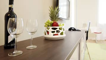 A table with a wine bottle, two glasses, and a fruit holder.