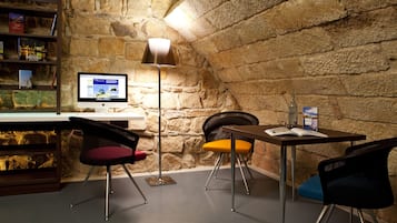 Eine gemütliche Leseecke mit einer Steinwand, einem Schreibtisch, einem Computer und zwei Stühlen.