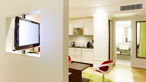 A modern kitchen with white cabinets, a microwave, and a coffee maker. There is a dining area with a wooden table and a red chair. - Hapimag Resort Dresden (Dresden)
