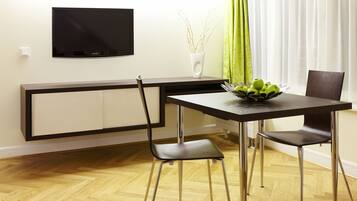 Un moderno comedor con una televisión de pantalla plana en la pared, una mesa con sillas y un jarrón con ramas a un lado.