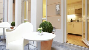 A modern hotel lobby with white furniture, a small potted plant, and a view into the kitchen area. - Hapimag Resort Dresden (Dresden)