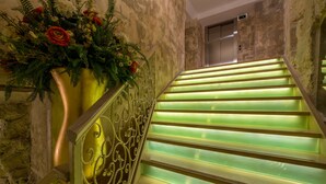 A staircase with green-lit steps and a decorative wall on the left. - Plaza Marchi Old Town - MAG Quaint & Elegant Boutique Hotels (Split)