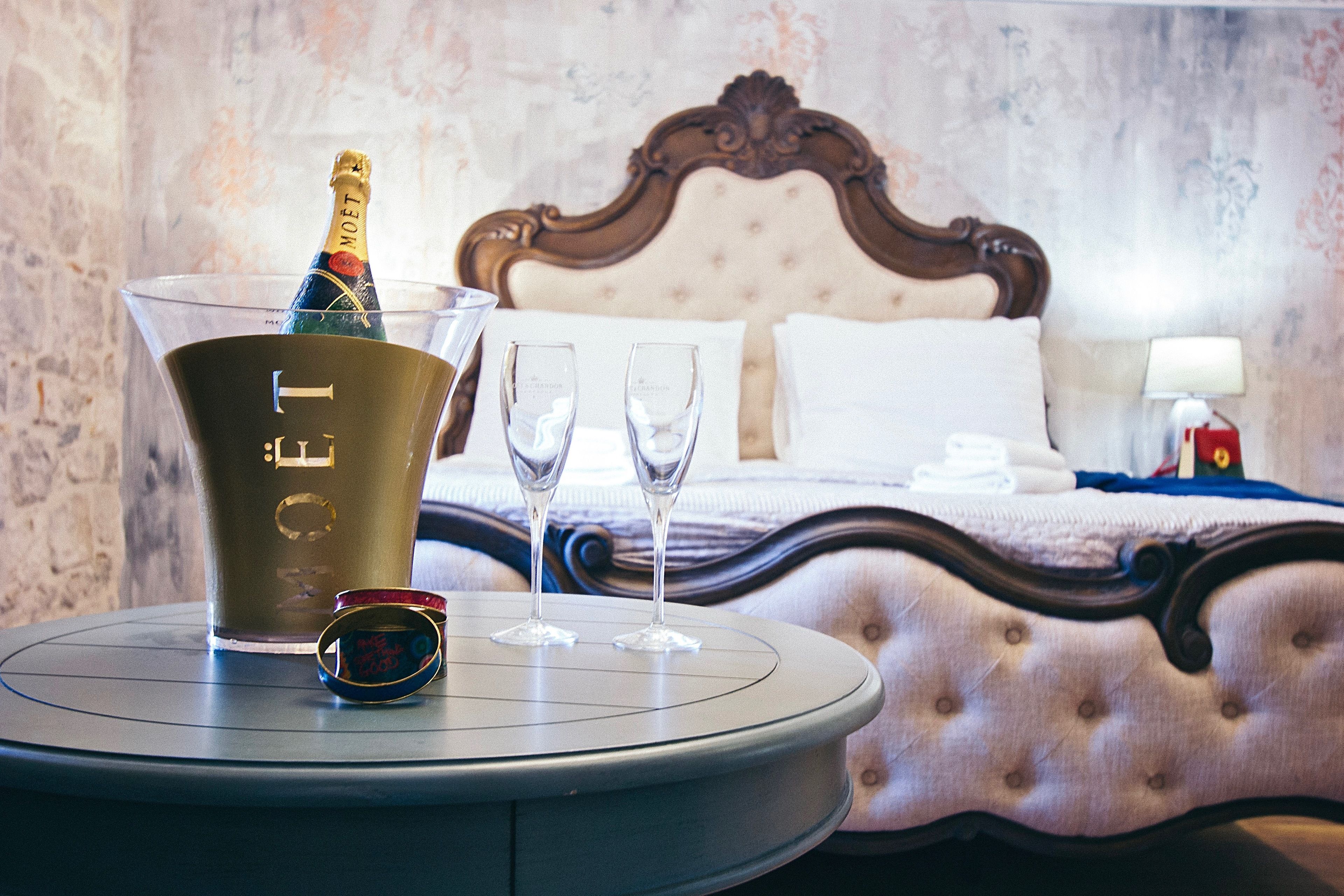 Un mini-bar avec une bouteille de champagne, deux verres et une paire de lunettes de soleil, le tout posé sur une table ronde.