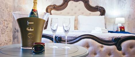Un mini-bar avec une bouteille de champagne, deux verres et une paire de lunettes de soleil, le tout posé sur une table ronde.