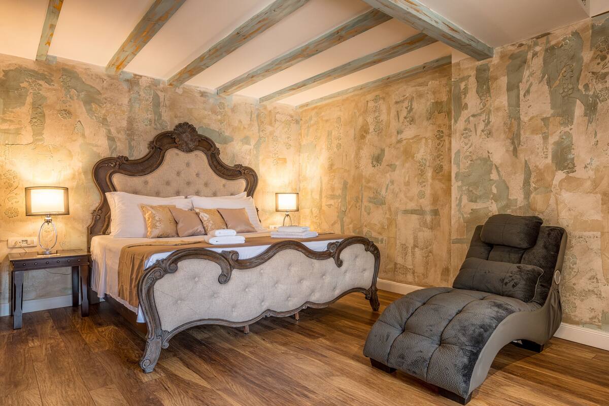 Ein Schlafzimmer mit einem großen Bett, einem Nachttisch, einer Leselampe und einem Liegesessel.