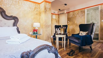 Habitación de hotel con una cama grande, una silla, una mesita con lámpara y un minibar.