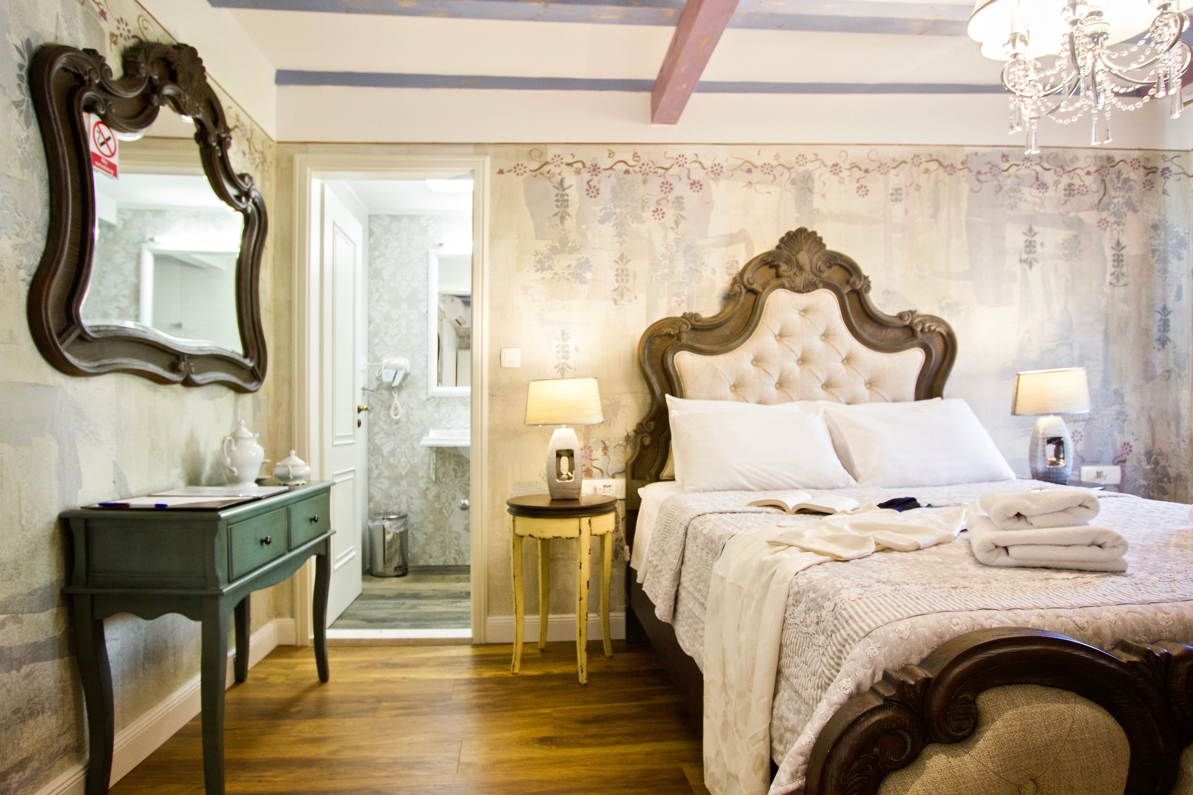 A bedroom with a large bed, two bedside tables with lamps, a dresser, and a mirror.