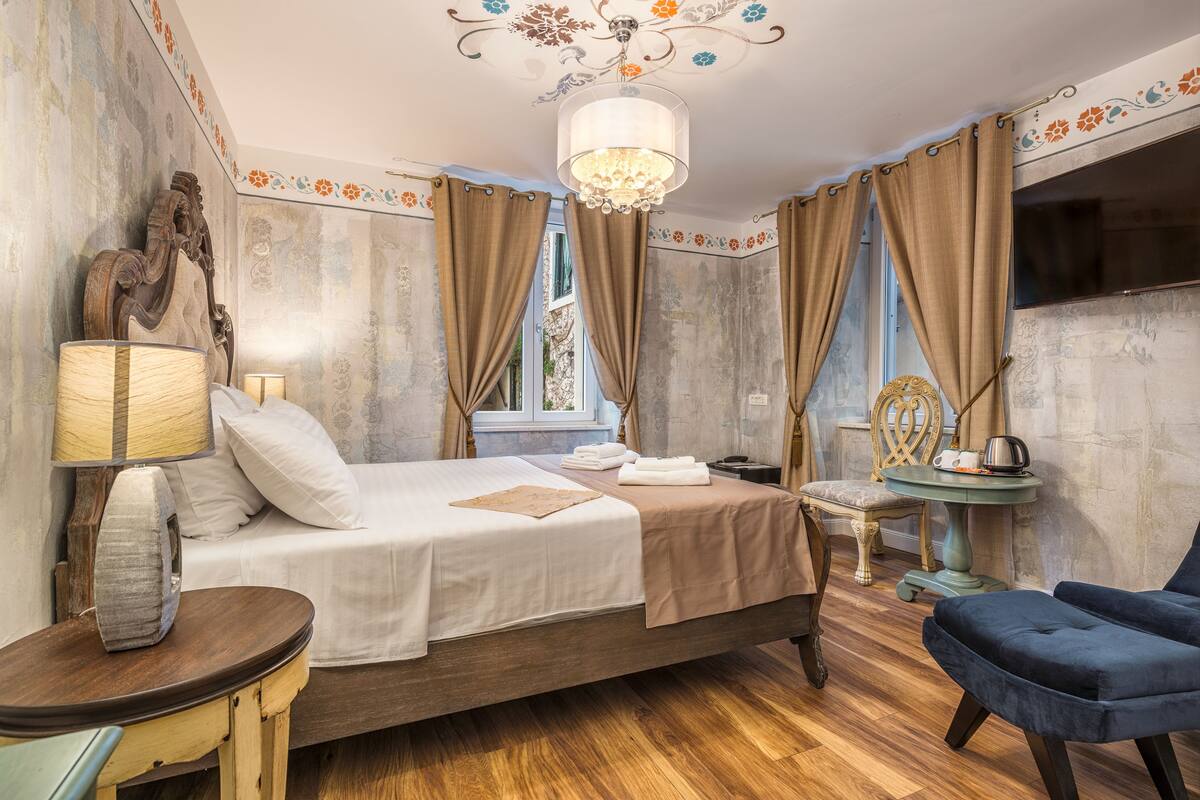 Ein Schlafzimmer mit Bett, Stuhl, Tisch und einer Chandeliebre.