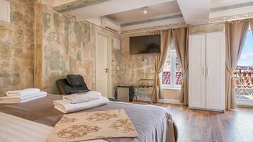 A hotel room with a bed, a massage chair, a small table, and a TV.