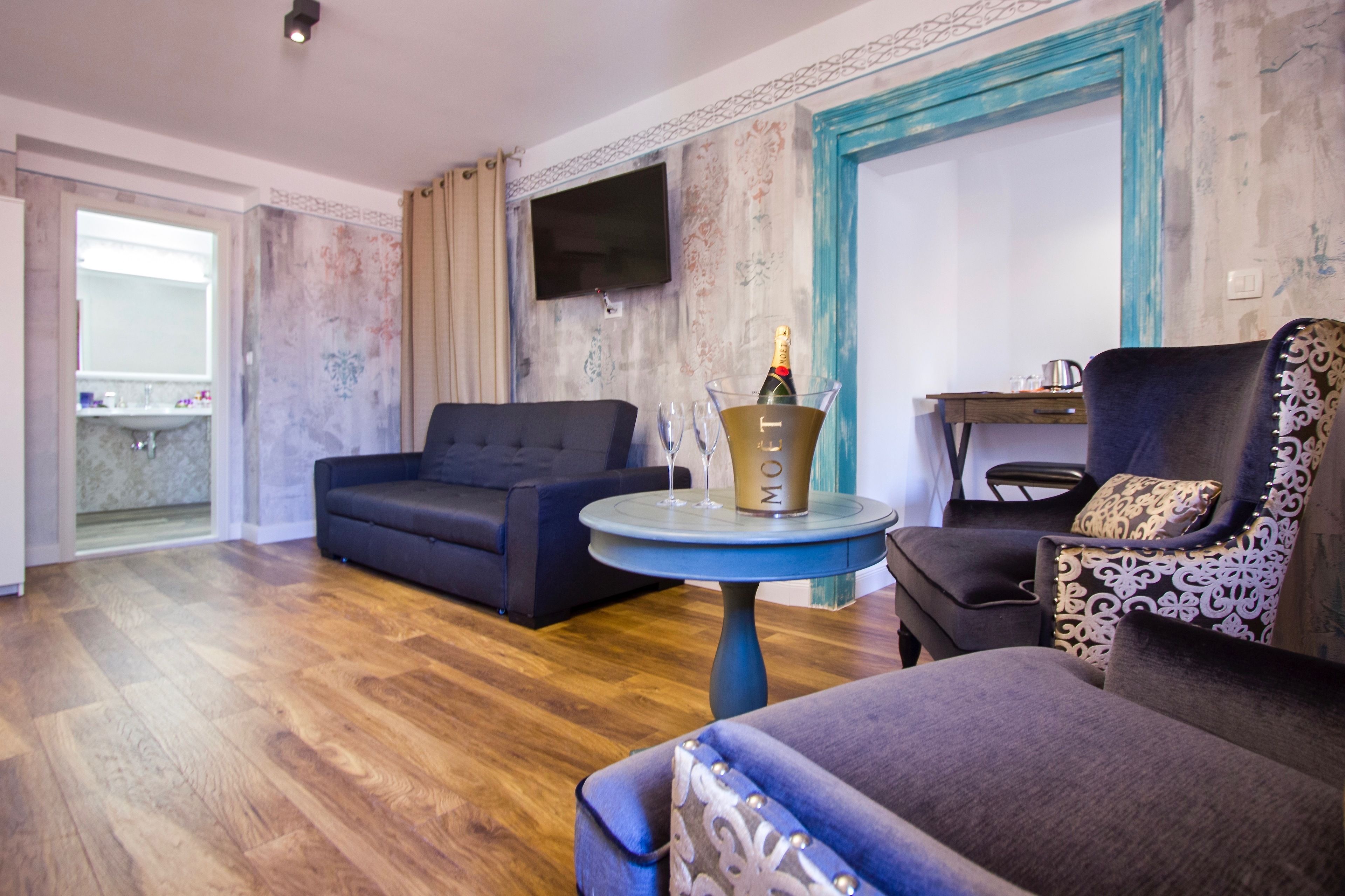 A living room with a sofa, armchair, and a table with a bottle and glasses.