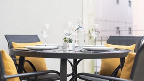 A round dining table with four chairs, each with a yellow cushion. The table is set with plates, glasses, and a small potted plant. - Apartment Alegria Street by Sweet Porto - Free Parking (Porto)