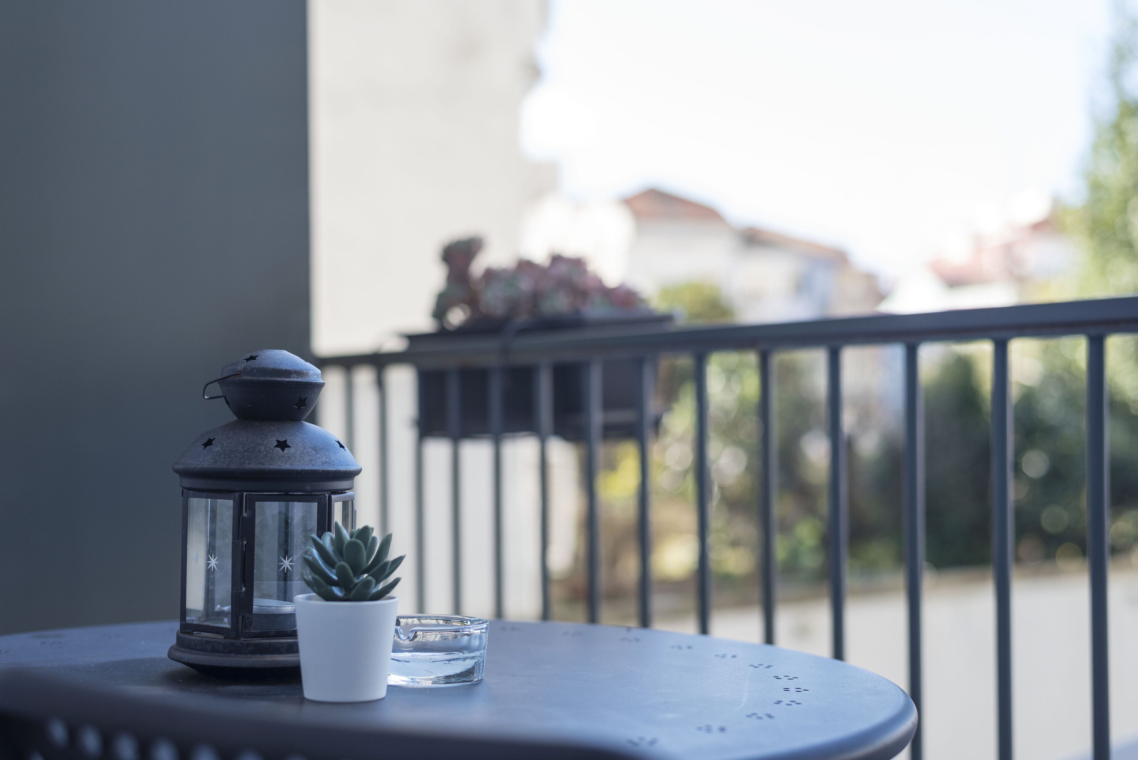 A balcony with a lantern, a small potted plant, and a glass.