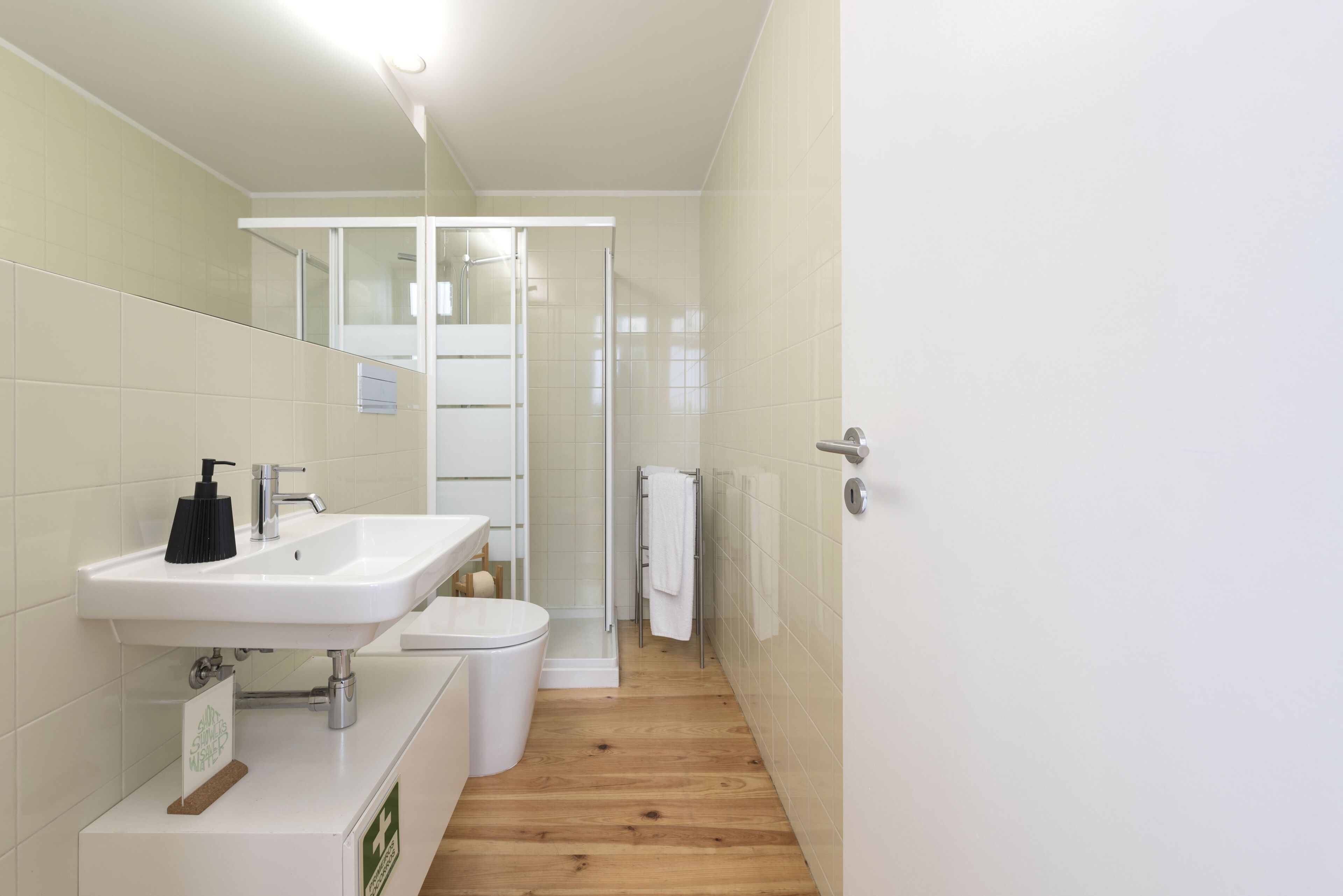 A modern bathroom with a white sink, mirror, and shower.