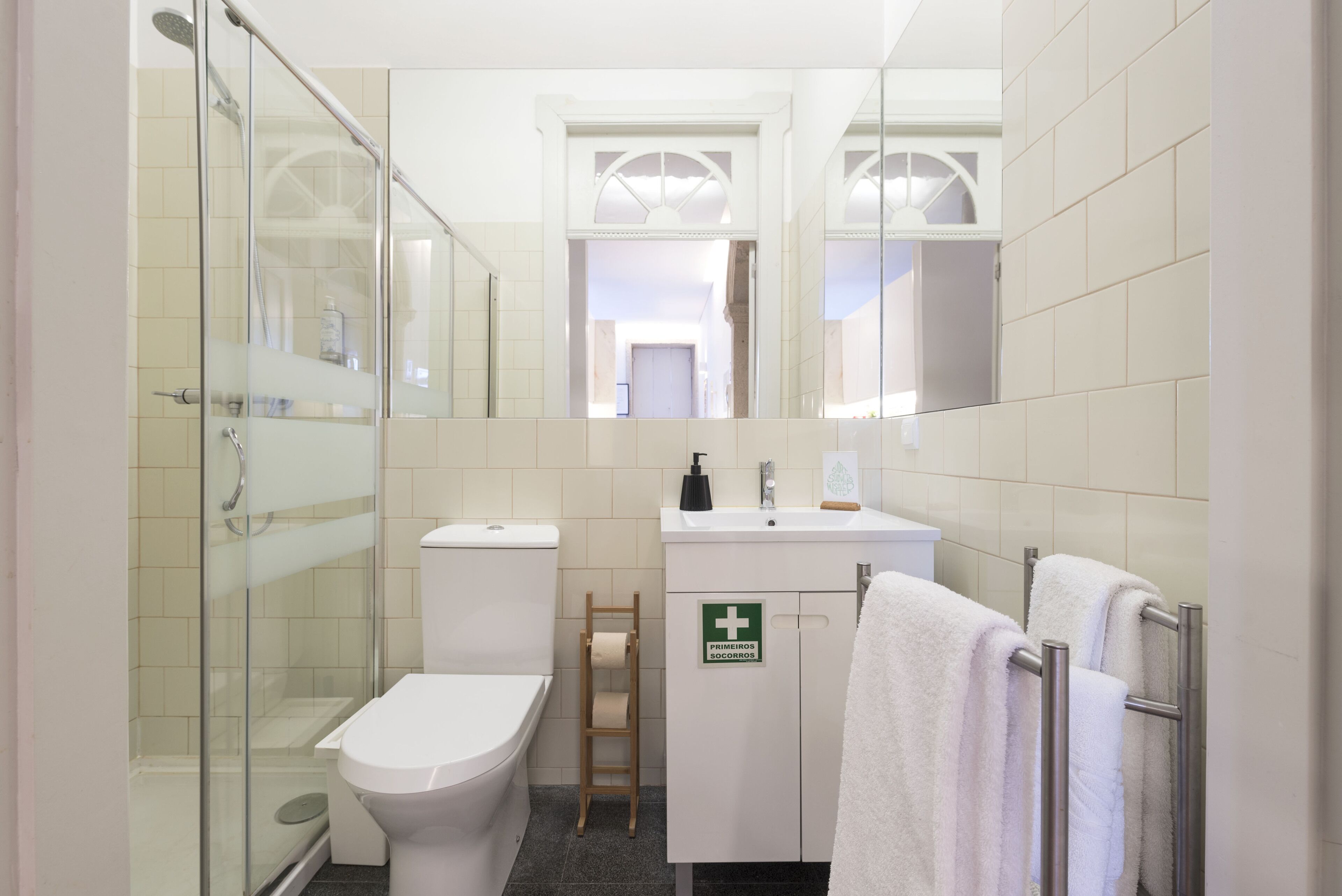 A bathroom with a glass shower enclosure, a toilet, a sink, and a towel rack.