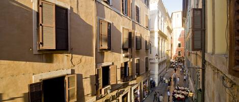 Una calle estrecha con edificios con ventanas con contraventanas y zonas de estar al aire libre.