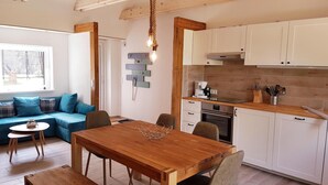 A modern kitchen with white cabinets, a wooden countertop, and a hanging light fixture. - Naturhof Usedom (Mölschow)