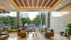 A modern lobby with leather sofas, a glass wall offering a view of the street, and a marble wall.