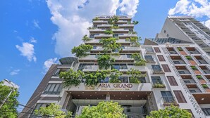 A multi-story hotel with balconies, a clear sky, and a sign reading "ARIA GRAND HOTEL".