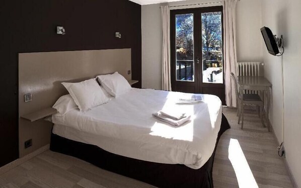Un dormitorio con una cama grande, una silla y una ventana con vistas al exterior.