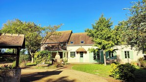 Une maison traditionnelle avec un toit en pente, une véranda et un jardin bien entretenu.