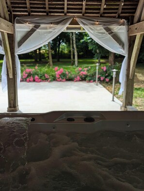 A gazebo with a view of a garden with pink flowers. - La Ferme Chauvet (Chantenay-Villedieu)